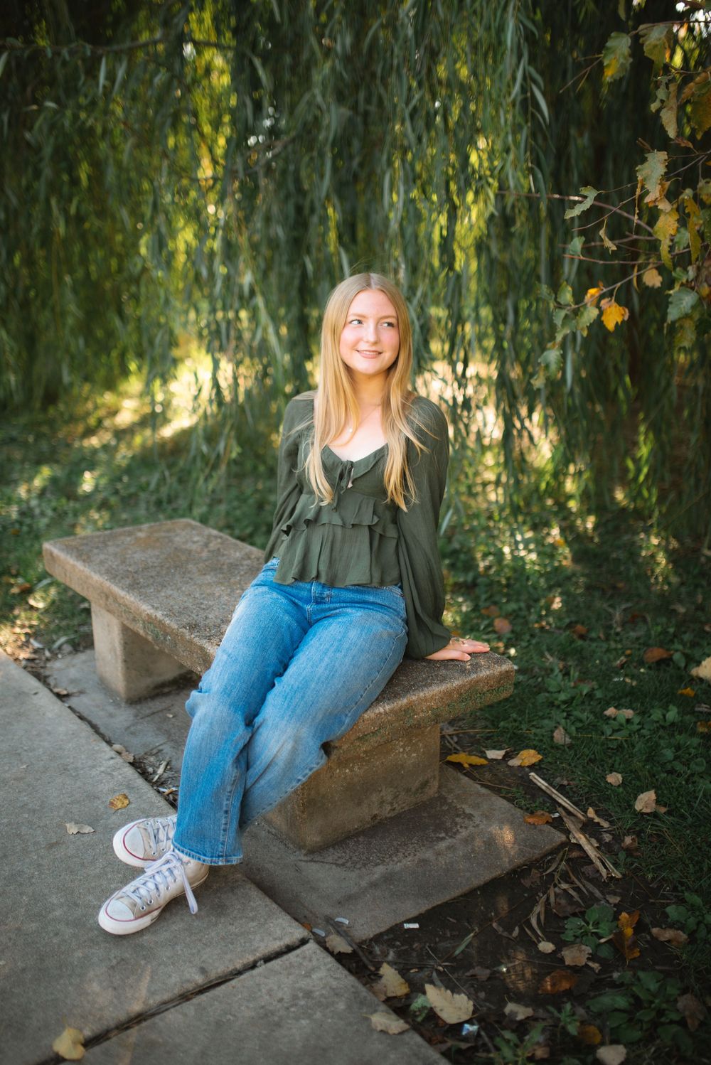 Relaxed outdoor portrait session on stone steps surrounded by autumn foliage and greenery.
