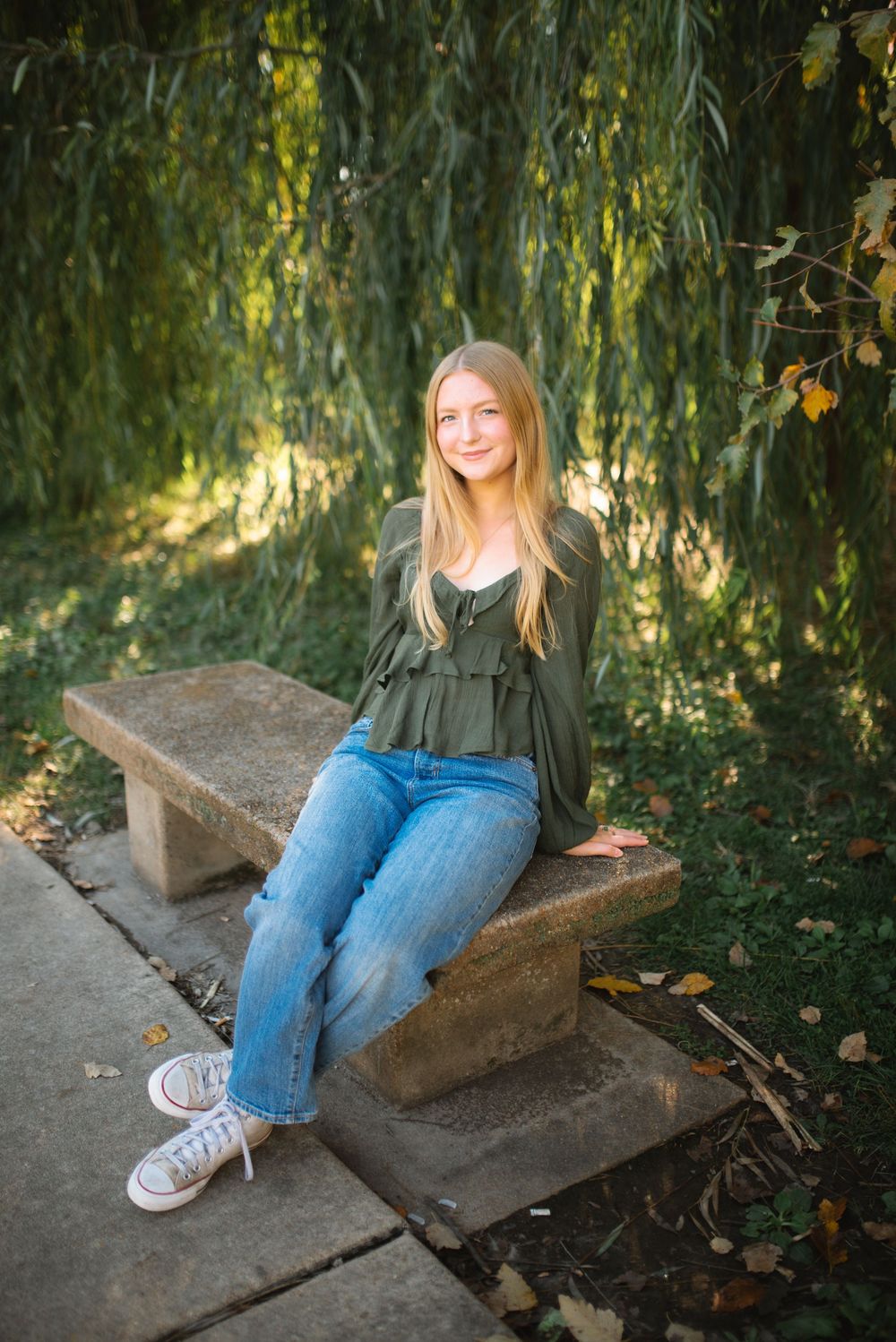 Casual outdoor portrait session on concrete steps surrounded by lush greenery and autumn foliage.