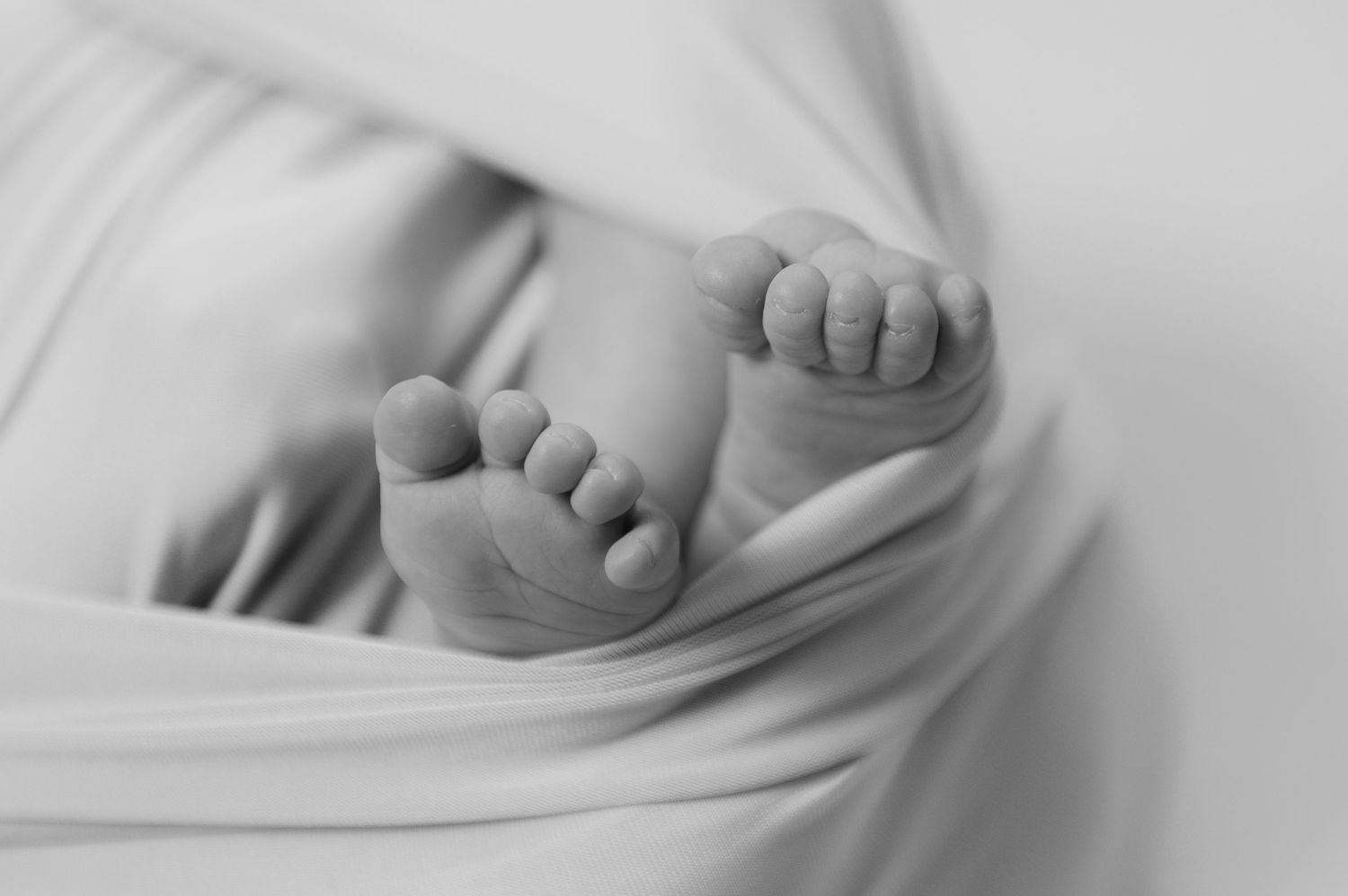 A series of black and white photographs showing close-up views of baby feet wrapped in soft blankets.