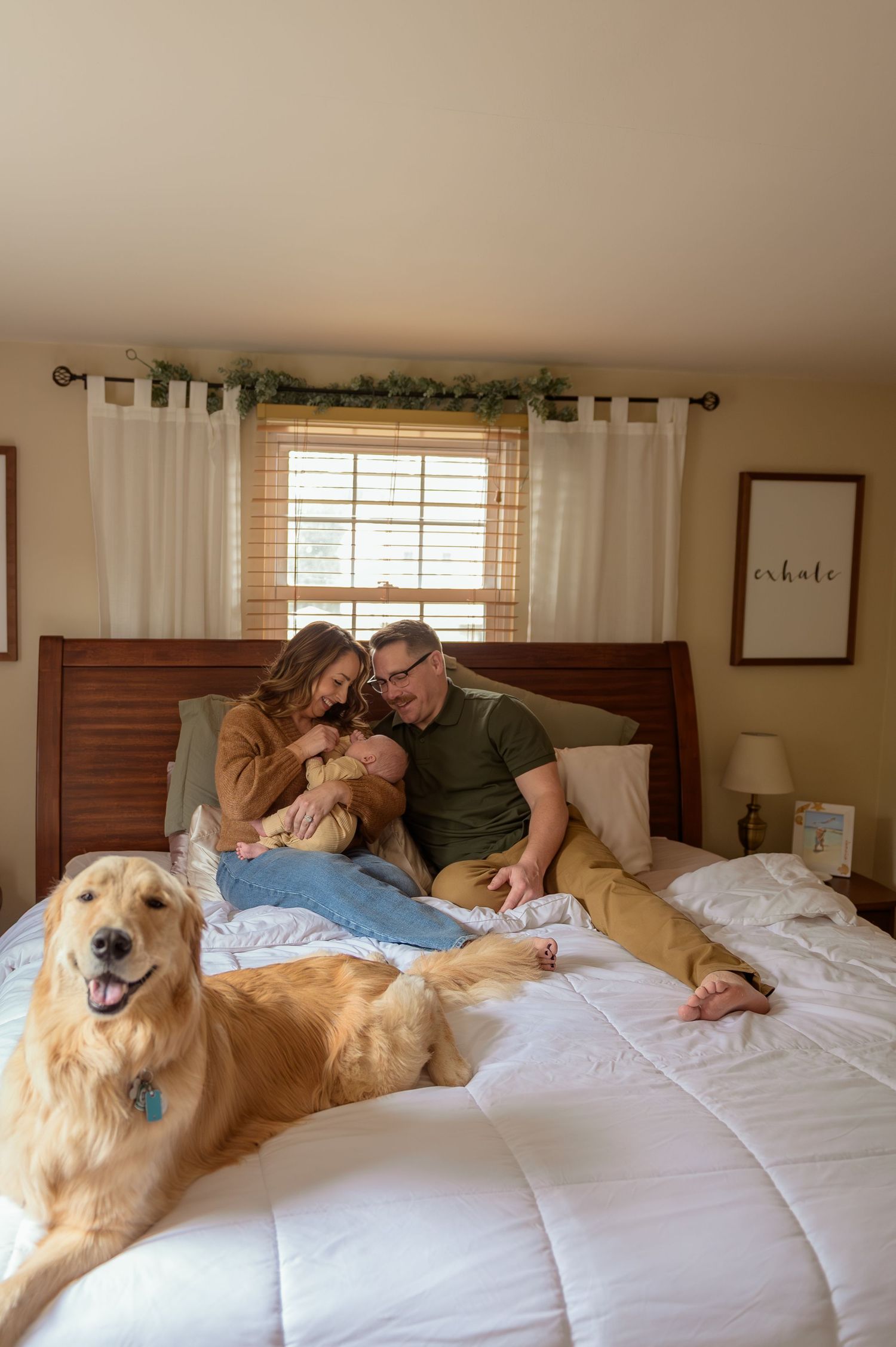 Golden retriever dog lies comfortably on white bedding while sharing tender moments with family members.