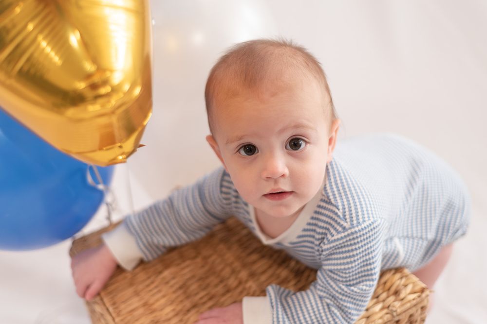 One year old boy crawling near balloons during first birthday session in Belton Texas