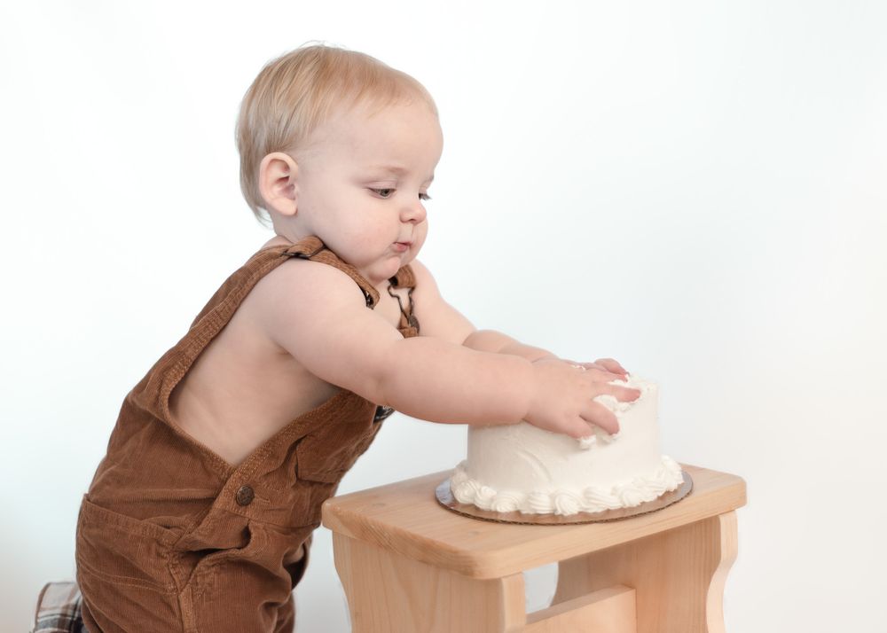One year old boy smashing cake during milestone session with a Harker Heights Texas baby photographer.