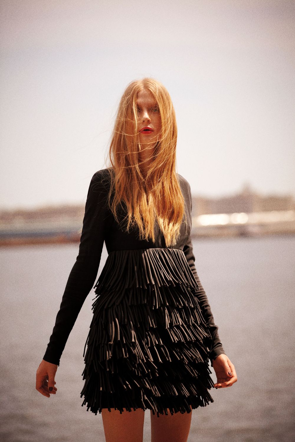 On location shot by Lauren Loncar. The model stands in front of a lake with a black dress on.