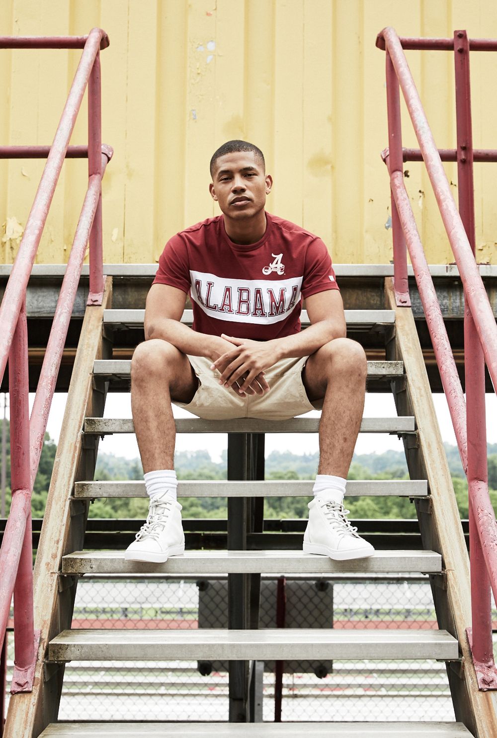 Model with an Alabama t-shirt sitting on steps at a high school stadium.