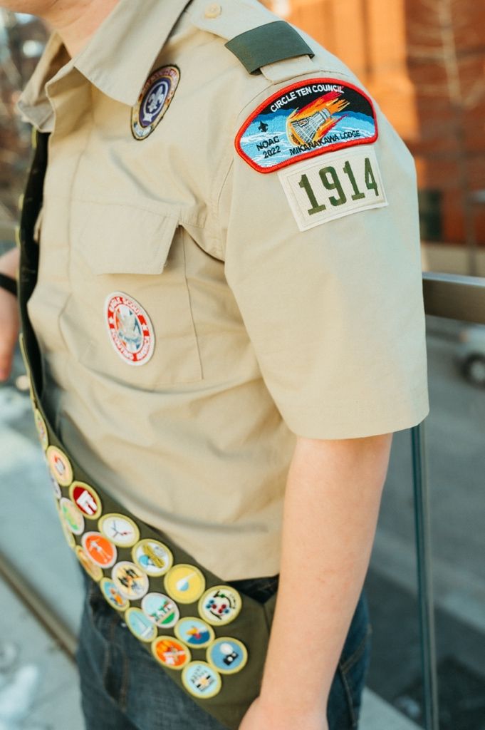 Detailed view of Scout uniform shoulder showing patches and merit badge sash.