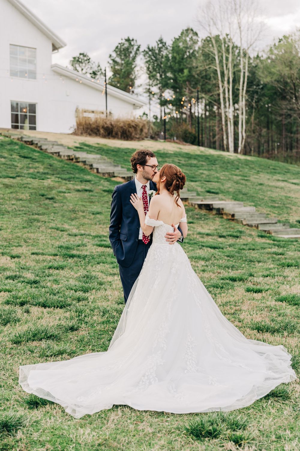 A romantic outdoor wedding photoshoot on a grassy hillside with a flowing white ballgown dress.