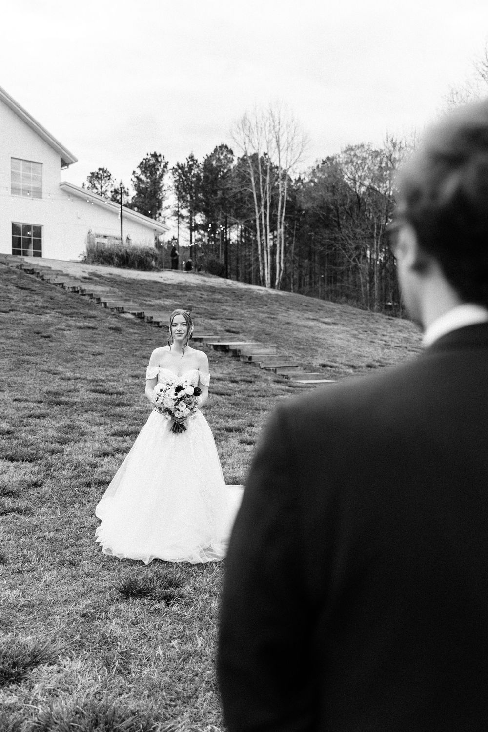 Black and white wedding photo with church and rolling hills in background.