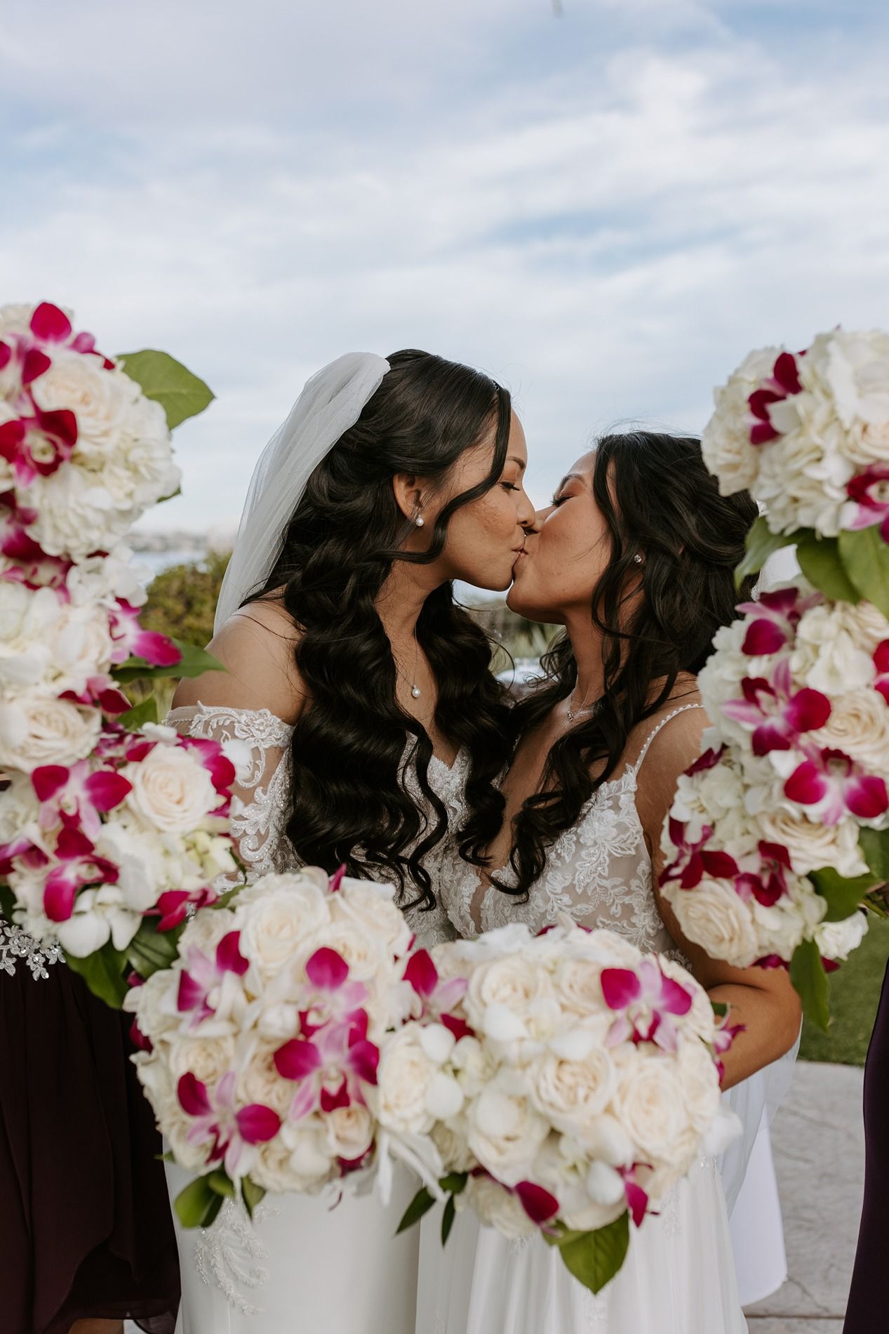Beautiful wedding scene with white and pink orchids and white roses creating an elegant floral backdrop for two brides.