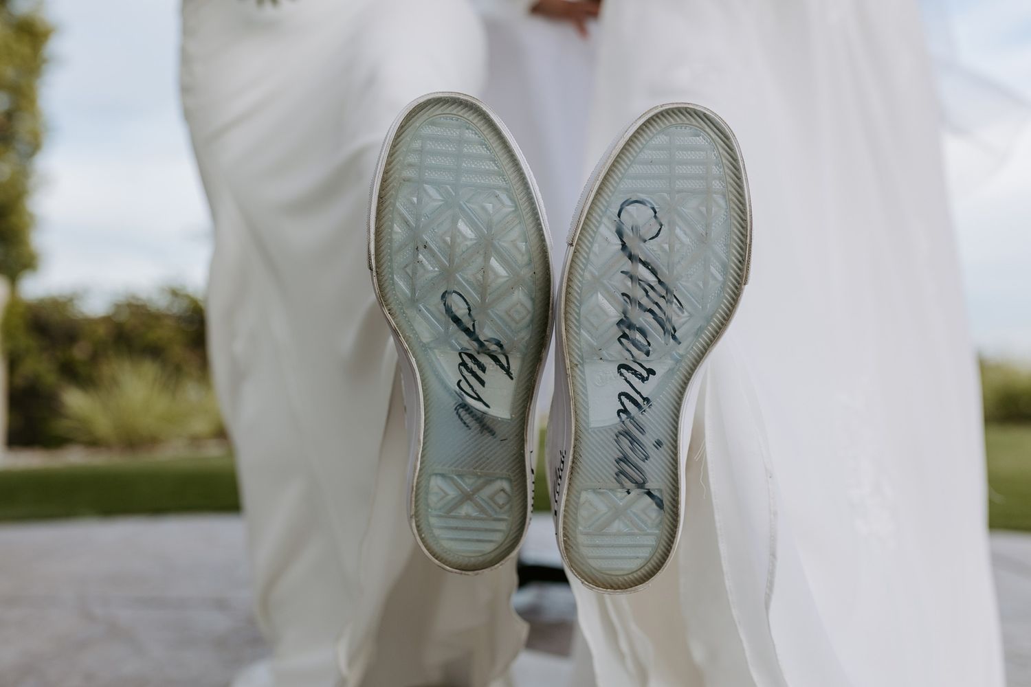 Two brides wearing custom wedding sneakers with writing on the soles with the message Just Married.