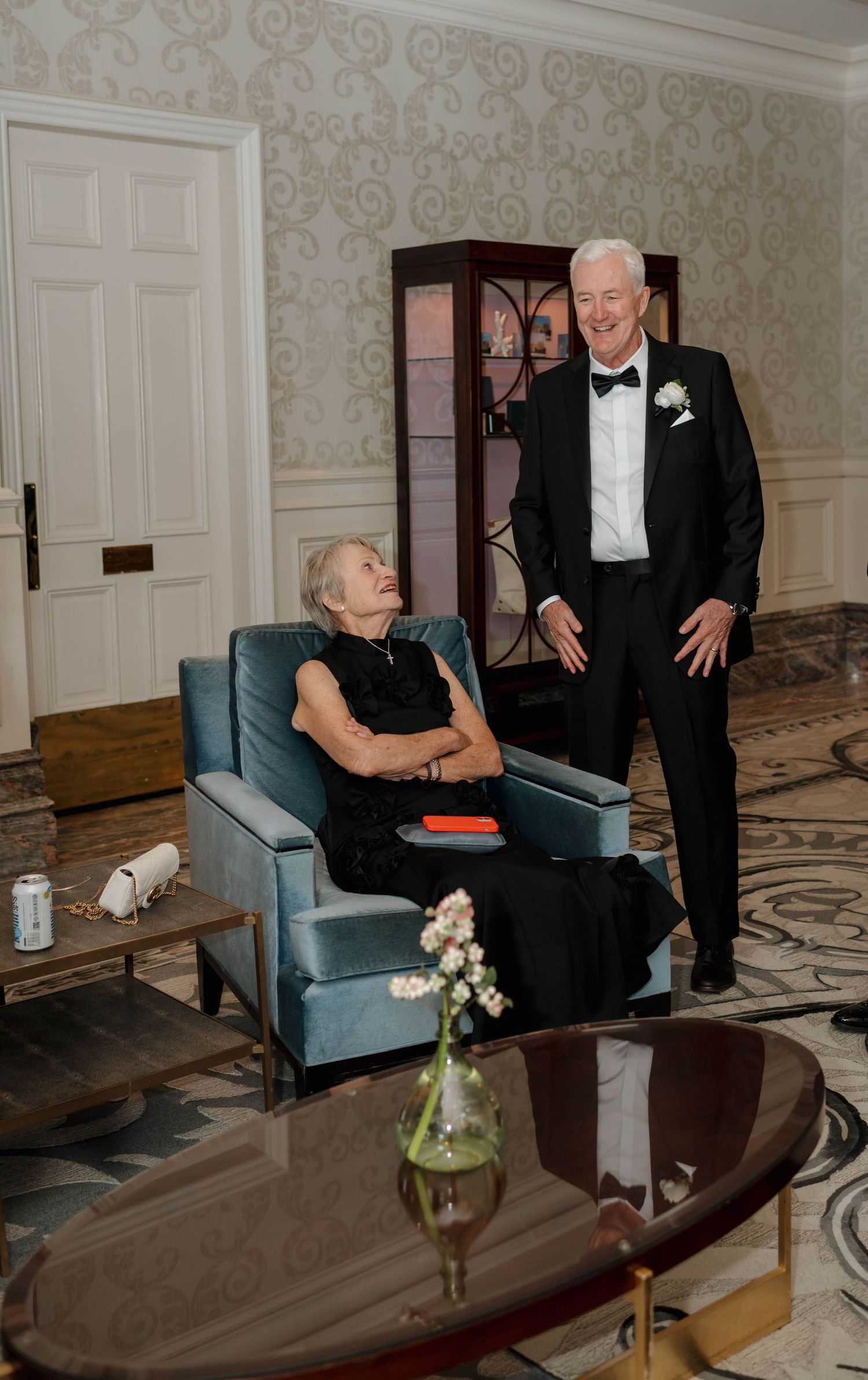 A sequence of four photos showing a person in a black dress seated on a blue chair while conversing with someone in formal attire.