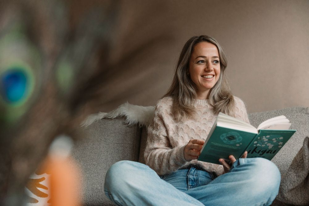 Relaxing reading scene on gray couch with book and warm sweater.