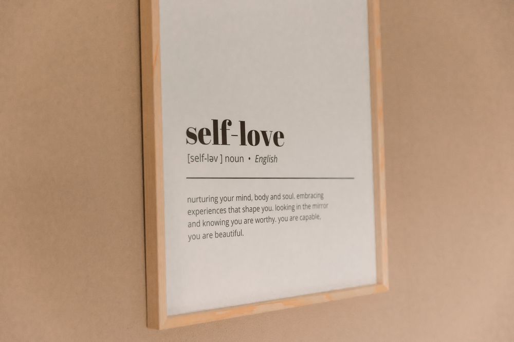 Minimalist self-love quote framed on beige wall.