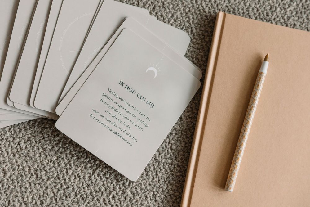 Minimalist stationery setup with cards, notebook and pencil on textured surface.