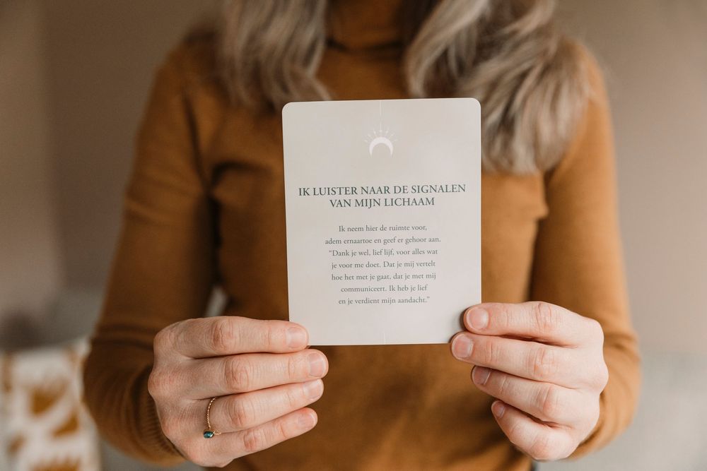 Hands holding minimalist quote card against warm brown background.