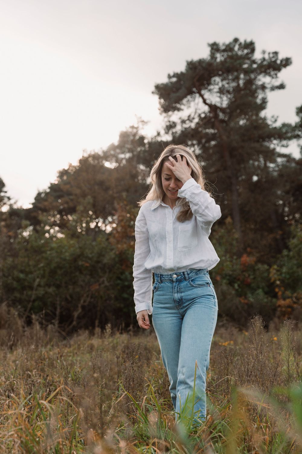 Casual outdoor photoshoot in field wearing white button-down and light denim.