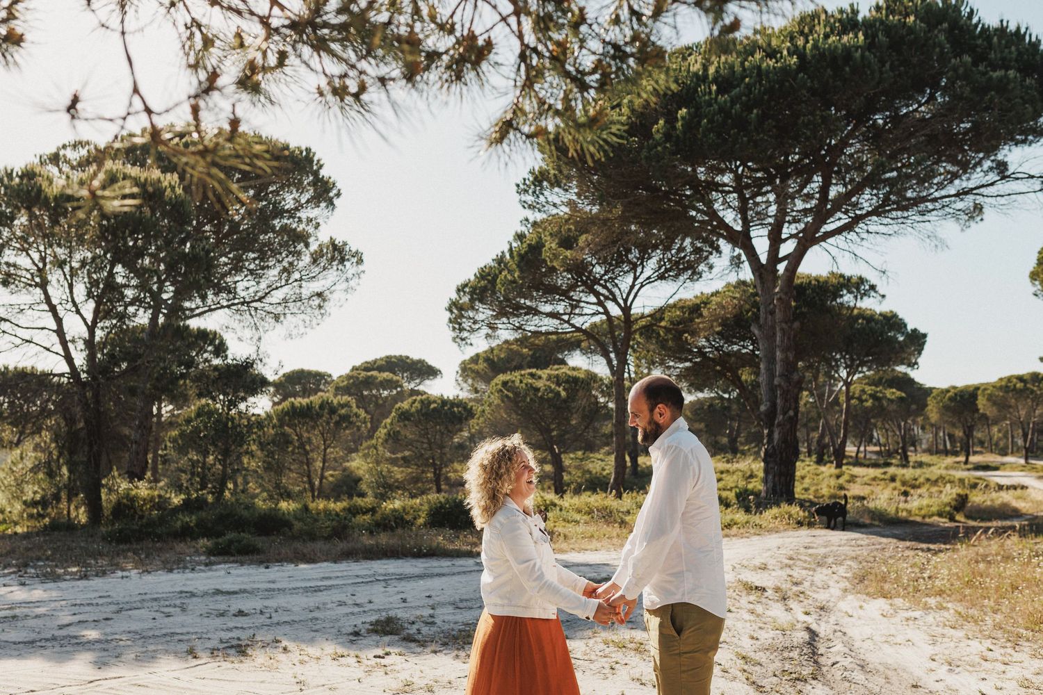 Couple laughing together during engagement photoshoot in Praia da Foz Portugal with pine trees