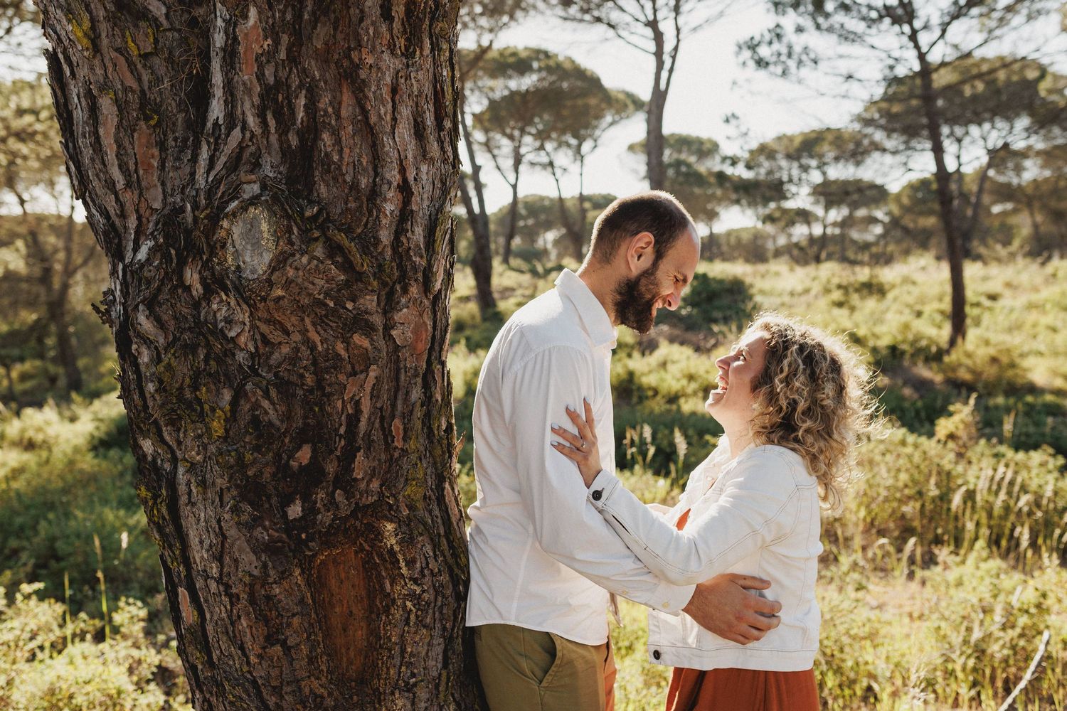 Engaged couple embracing under pine trees in natural landscape Praia da Foz Portugal