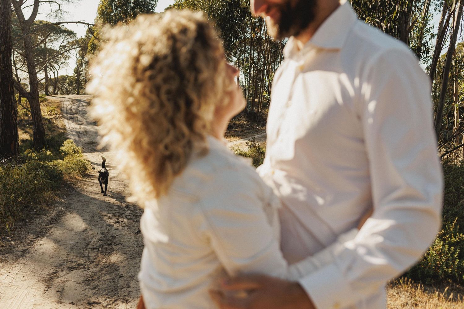 Romantic couple standing by tree in golden light during engagement session in Praia da Foz