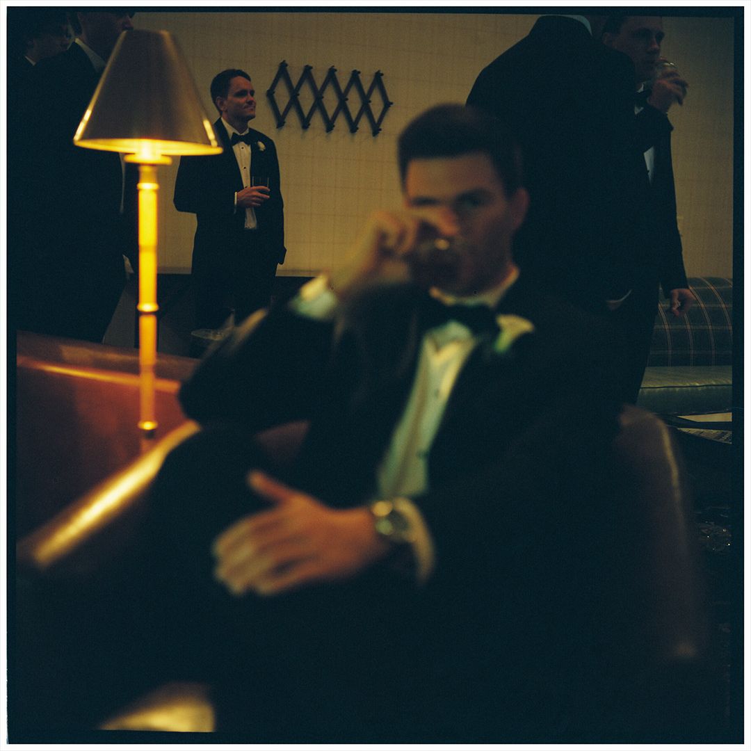 Professional bartender pouring drinks at an upscale bar counter in dim lighting.