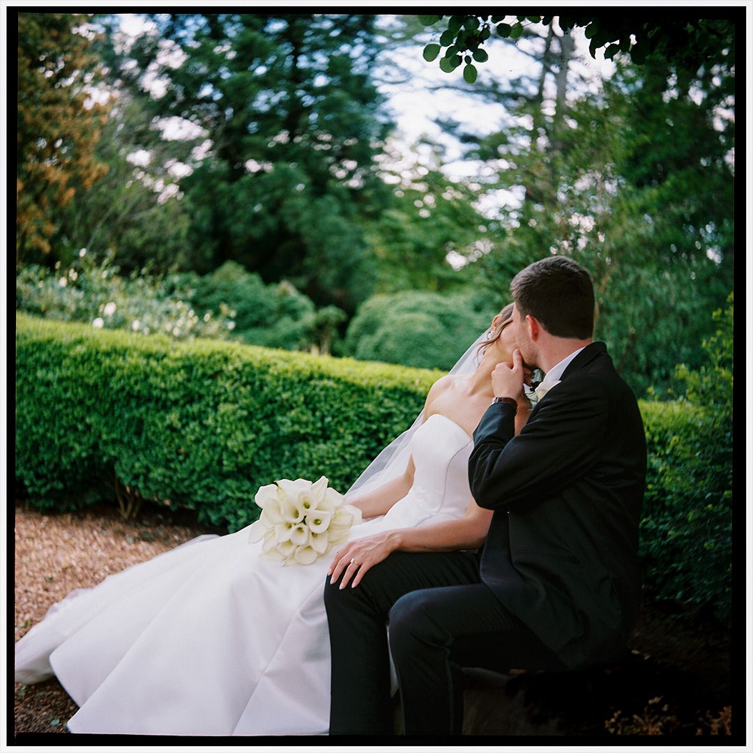 A romantic wedding couple shares tender moments in a lush garden setting during their outdoor photo session.