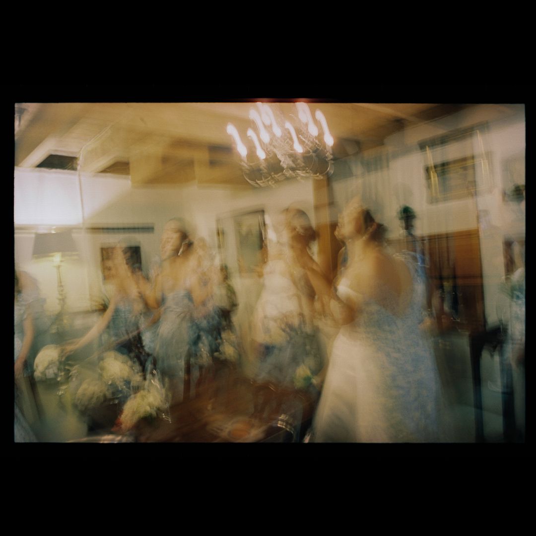 Multiple exposure photograph showing blurred figures moving through a bright interior space creating an ethereal effect.