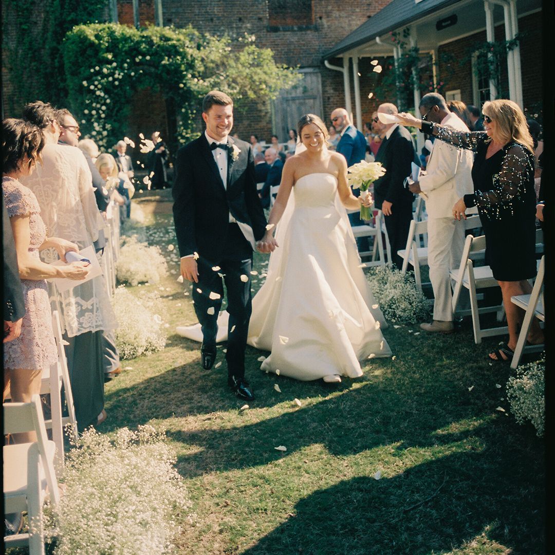 Wedding guests mingle and celebrate on a sunny garden lawn during an elegant outdoor reception celebration.