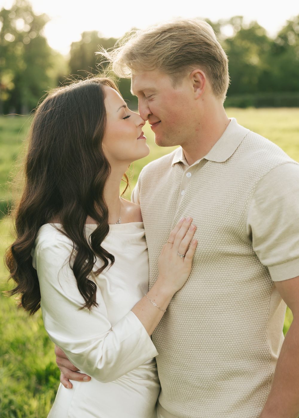 Couple sharing a romantic almost-kiss in a golden sunlit field during an outdoor engagement photo session.