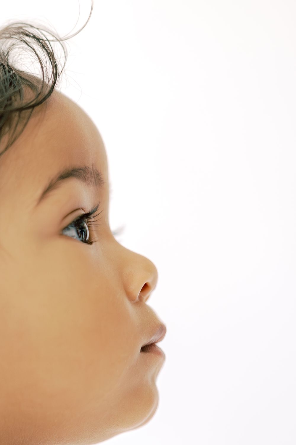 Close-up profile of a curious baby looking upward against a white background.