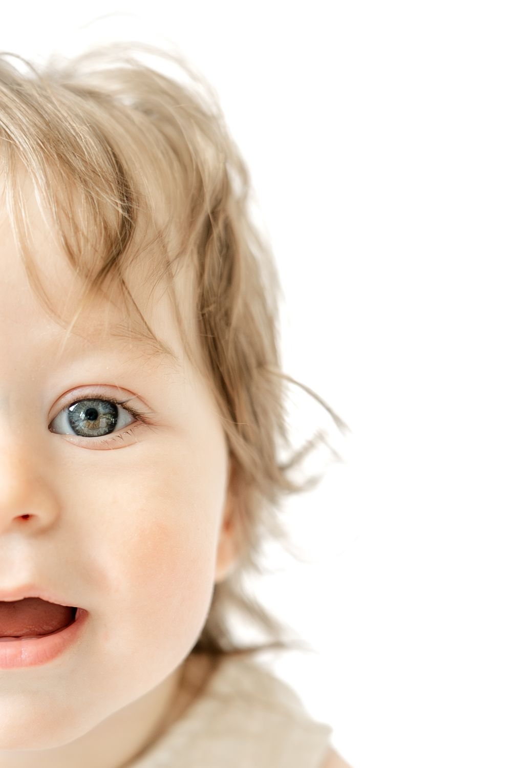 Close-up portrait of a happy toddler with blue eyes and blonde hair on a white background.