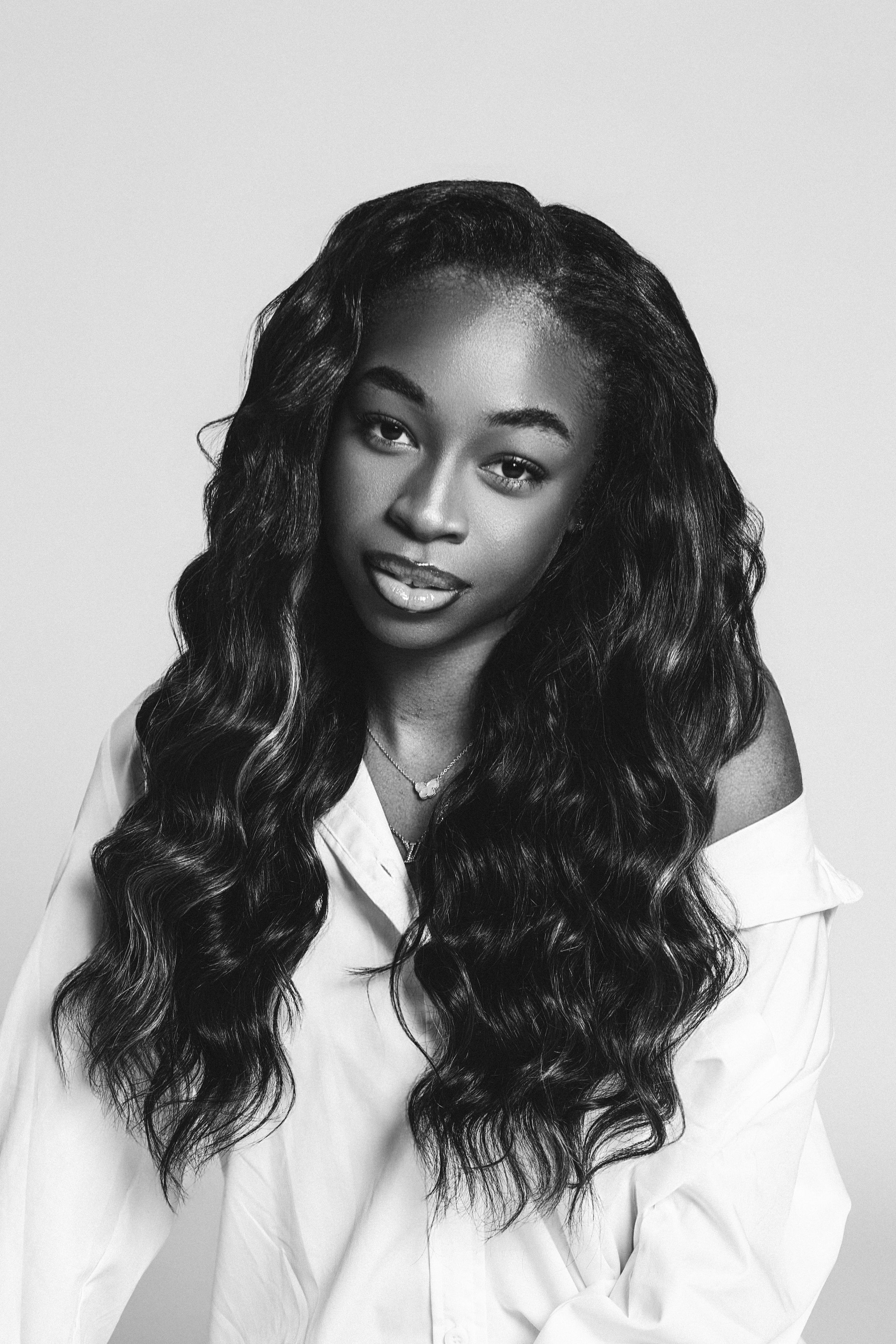 Portrait series of someone with flowing dark wavy hair wearing a white button-up shirt against a light background.
