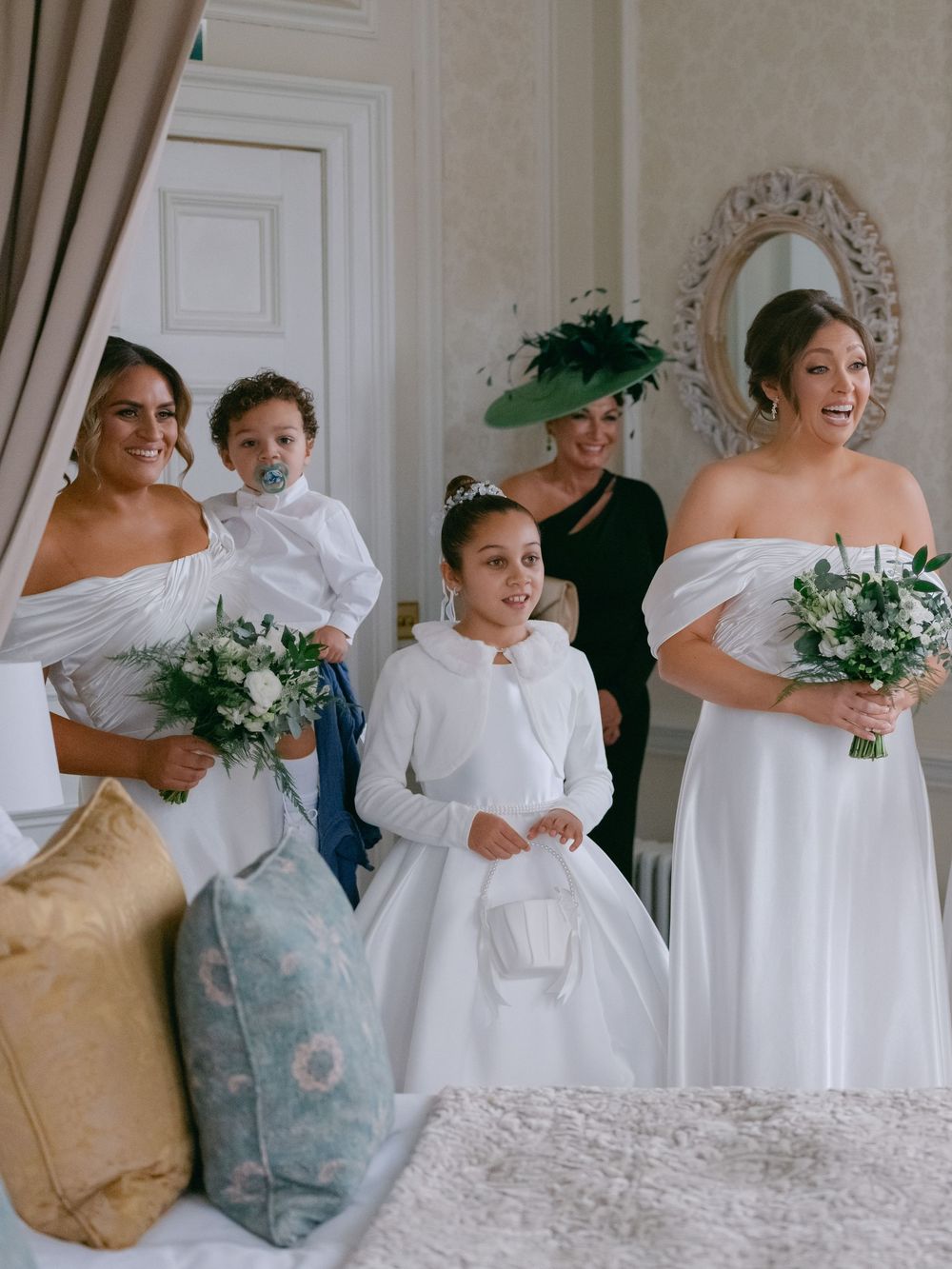 A group gathers in elegant white and neutral attire holding bouquets during a formal celebration.