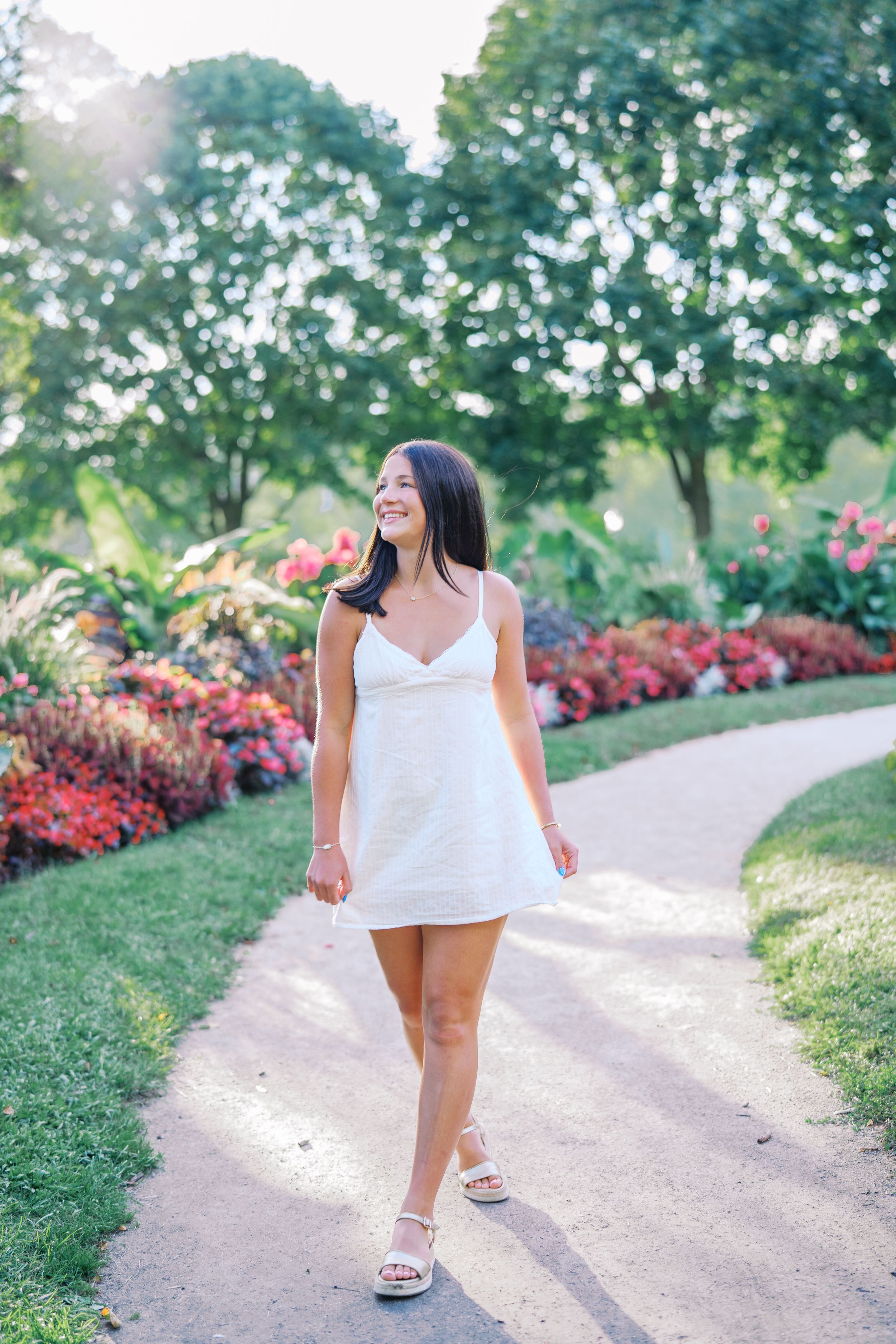 Sunlit portraits taken on a curved garden path bordered by colorful landscaping.