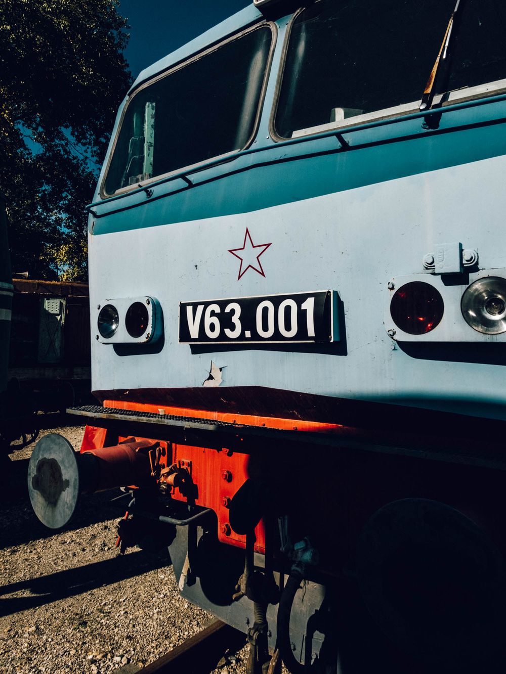 Vintage V63.001 locomotive with red star emblem and orange bumper displayed outdoors in natural light.