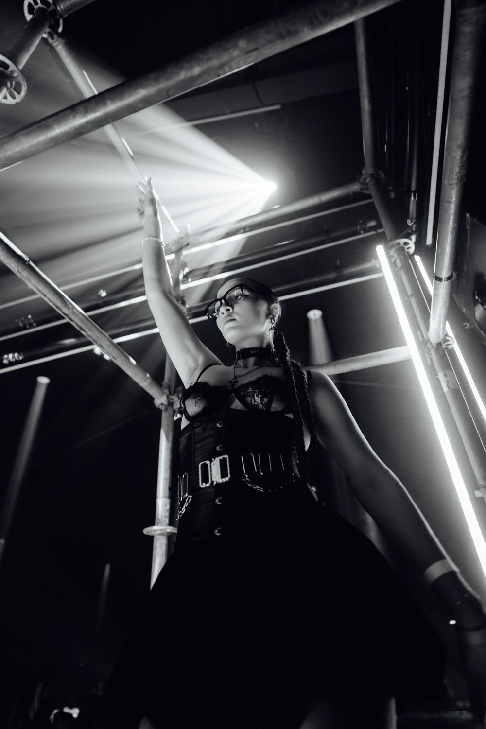 DJ photographed from below against industrial ceiling lights.