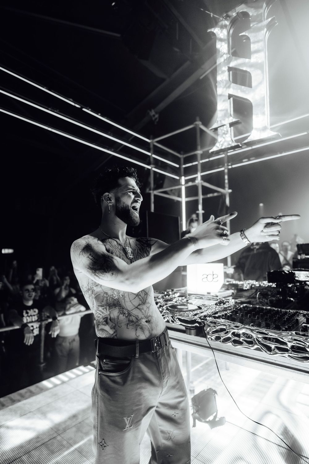 DJ performing energetically at mixing console in high contrast monochrome.