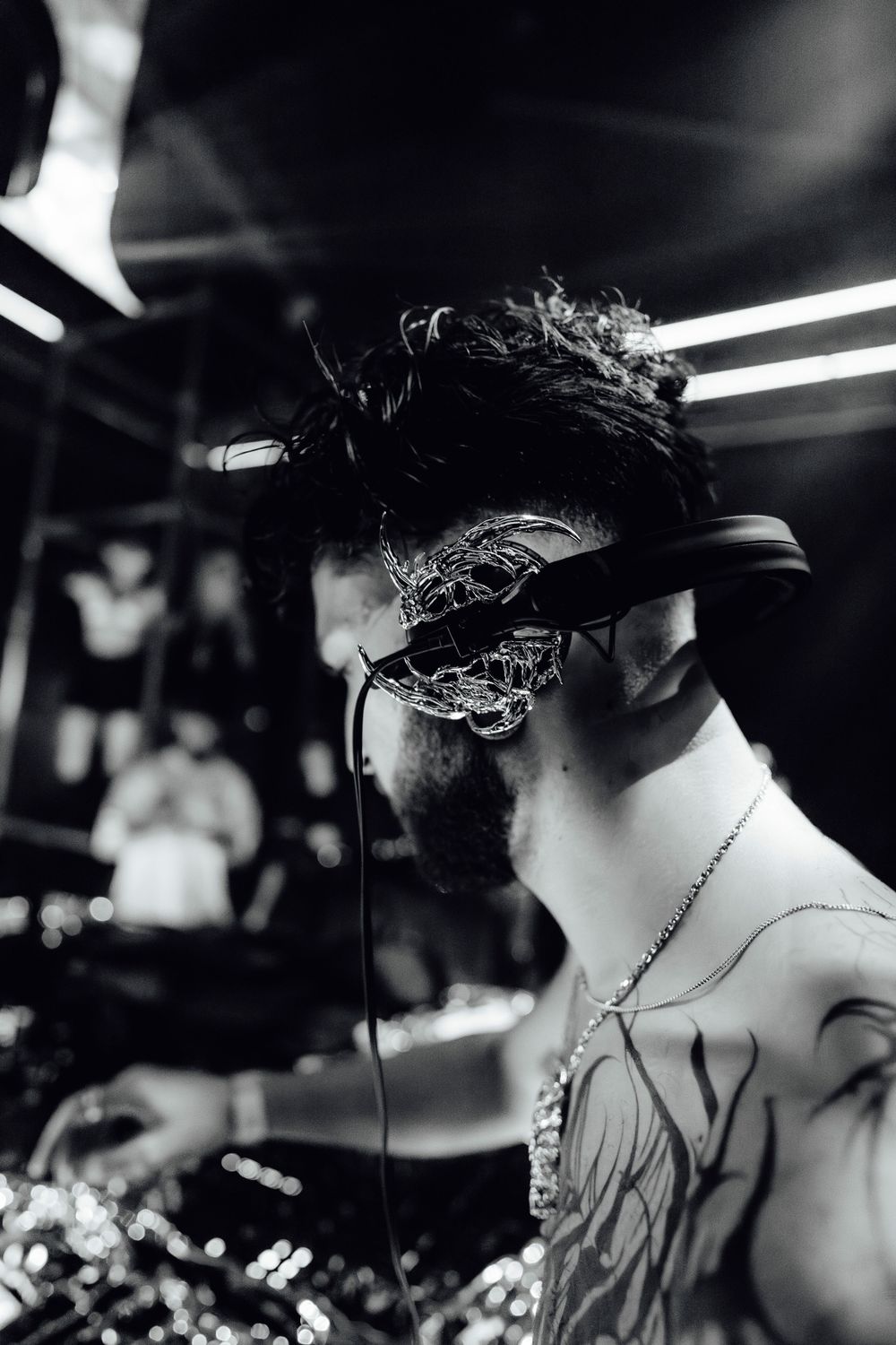 Black and white profile shot of a DJ performing at a nightclub with overhead lighting.