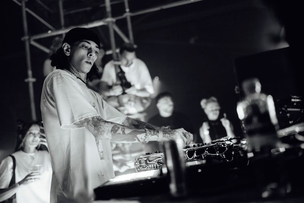 Panoramic black and white shot of a nightclub DJ setup with turntables and equipment.