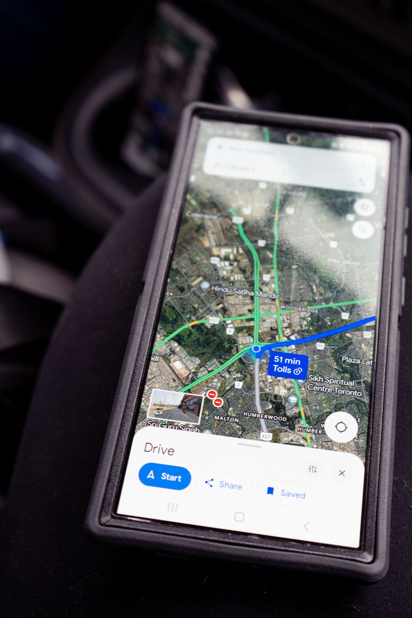 A smartphone displaying Google Maps navigation interface with satellite view and route guidance shown on the screen.