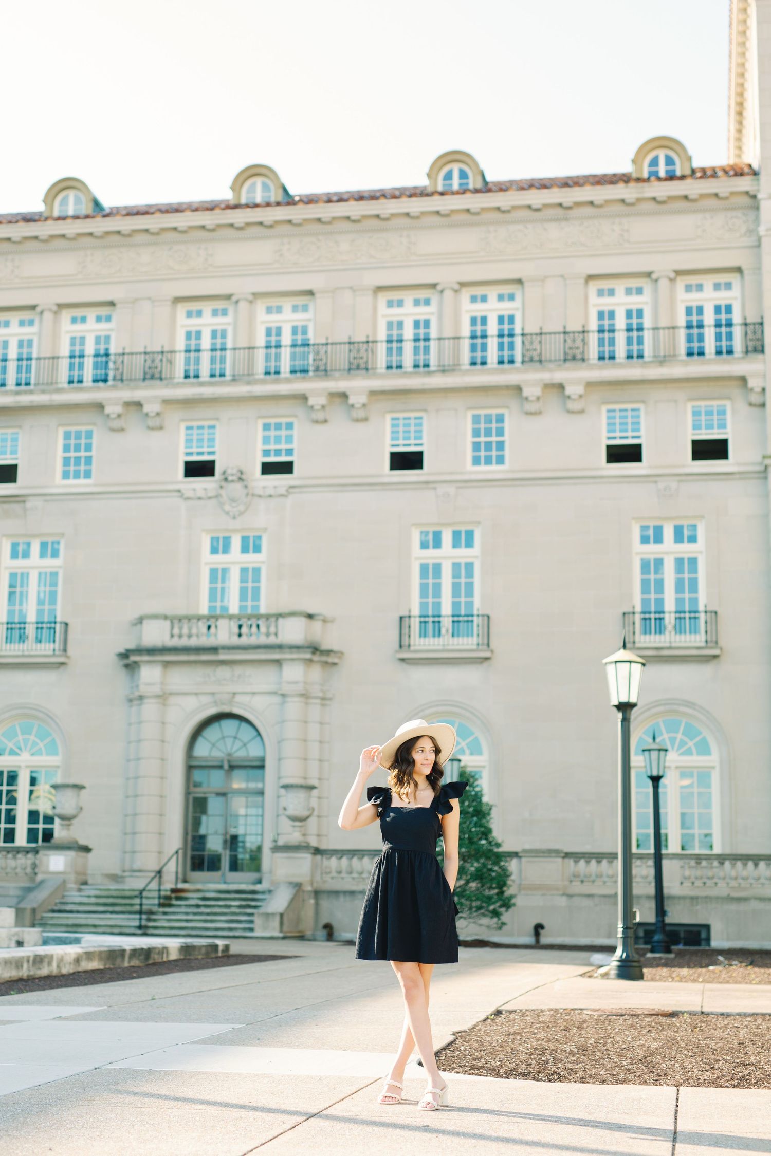 Elegant beige stone building with French windows and classic architecture with a person posing looking off to the side