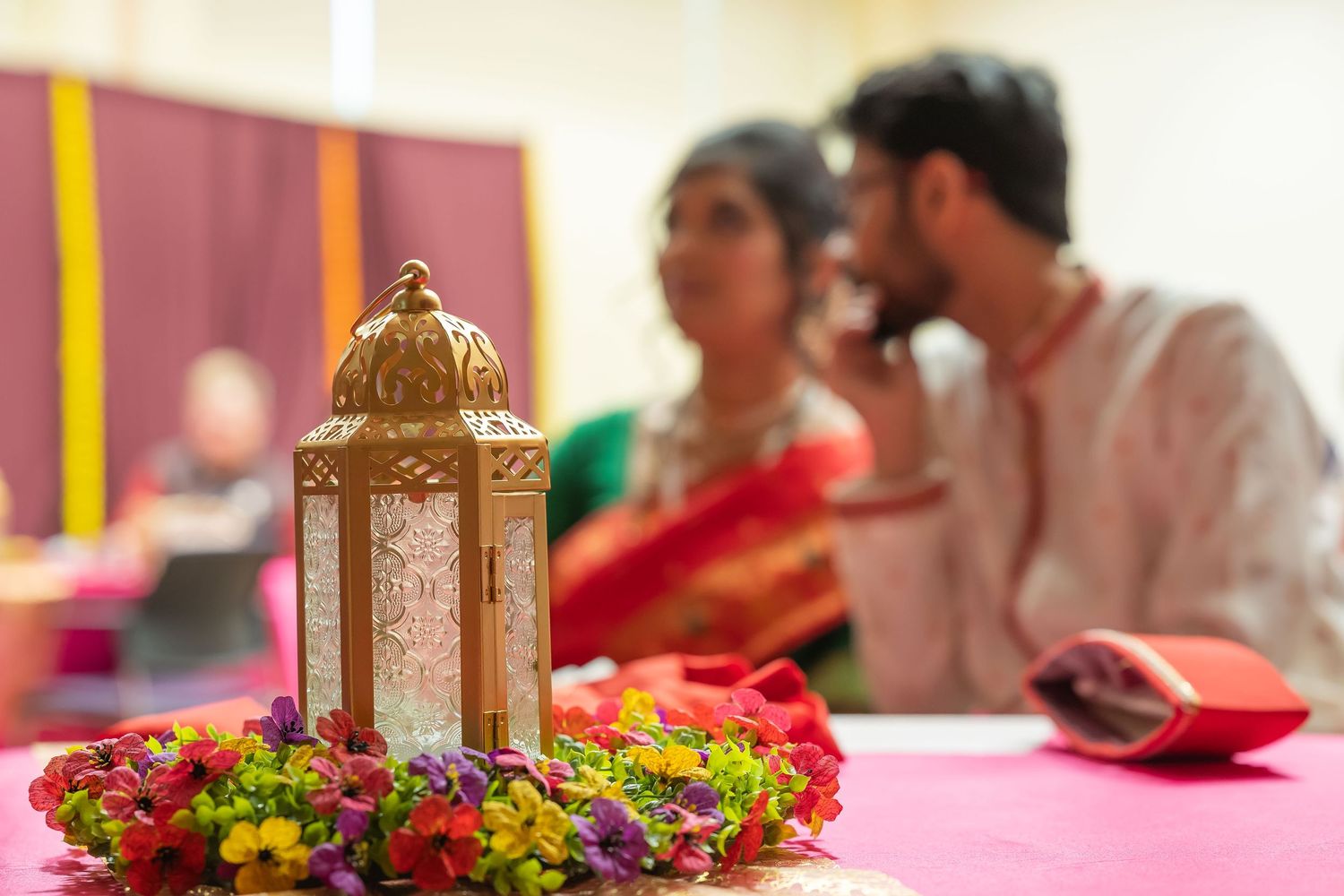 Golden decorative lantern with colorful flower wreath centerpiece at Indian wedding reception ceremony.