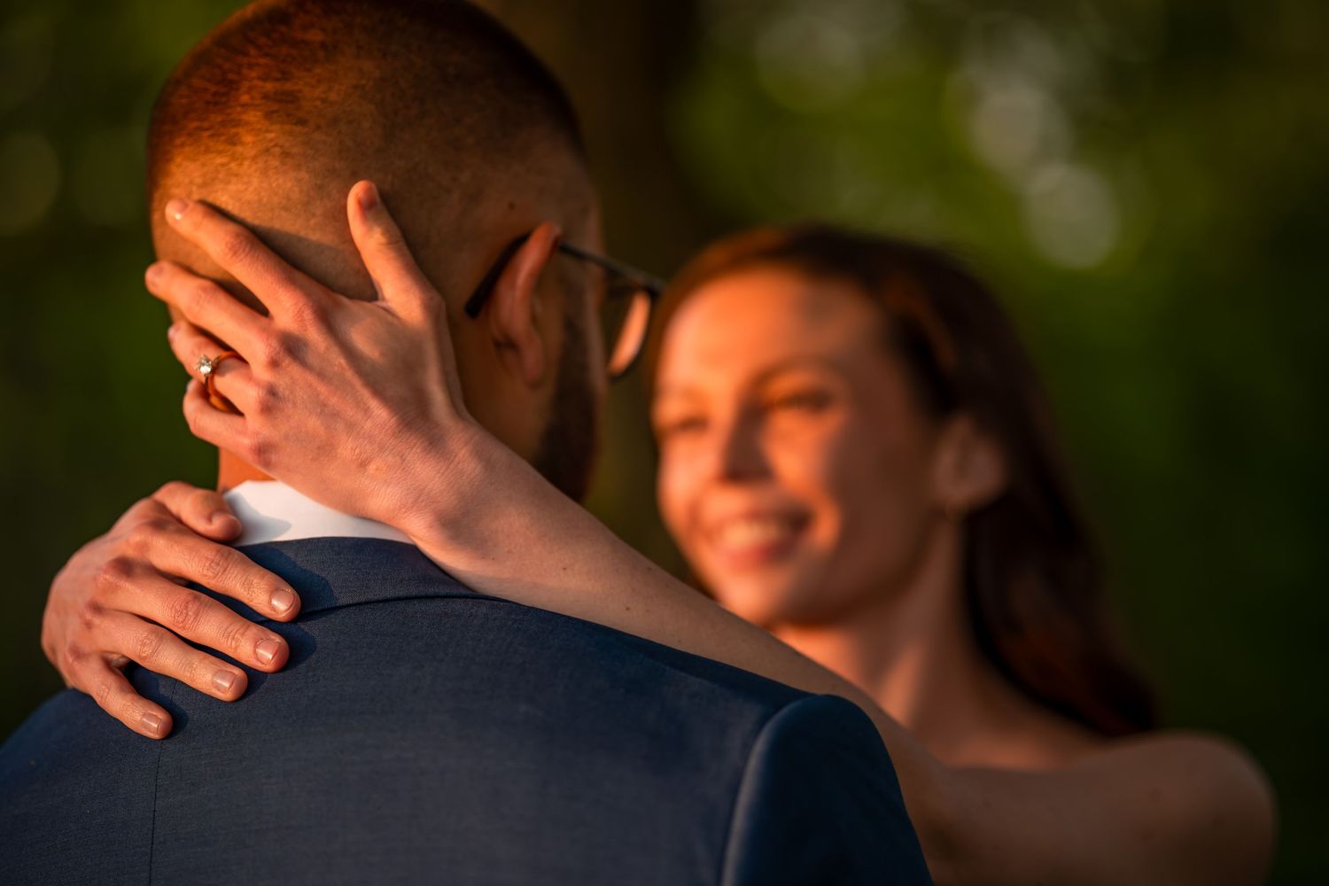Bride tenderly cups grooms face in her hand during romantic outdoor wedding portrait at sunset.