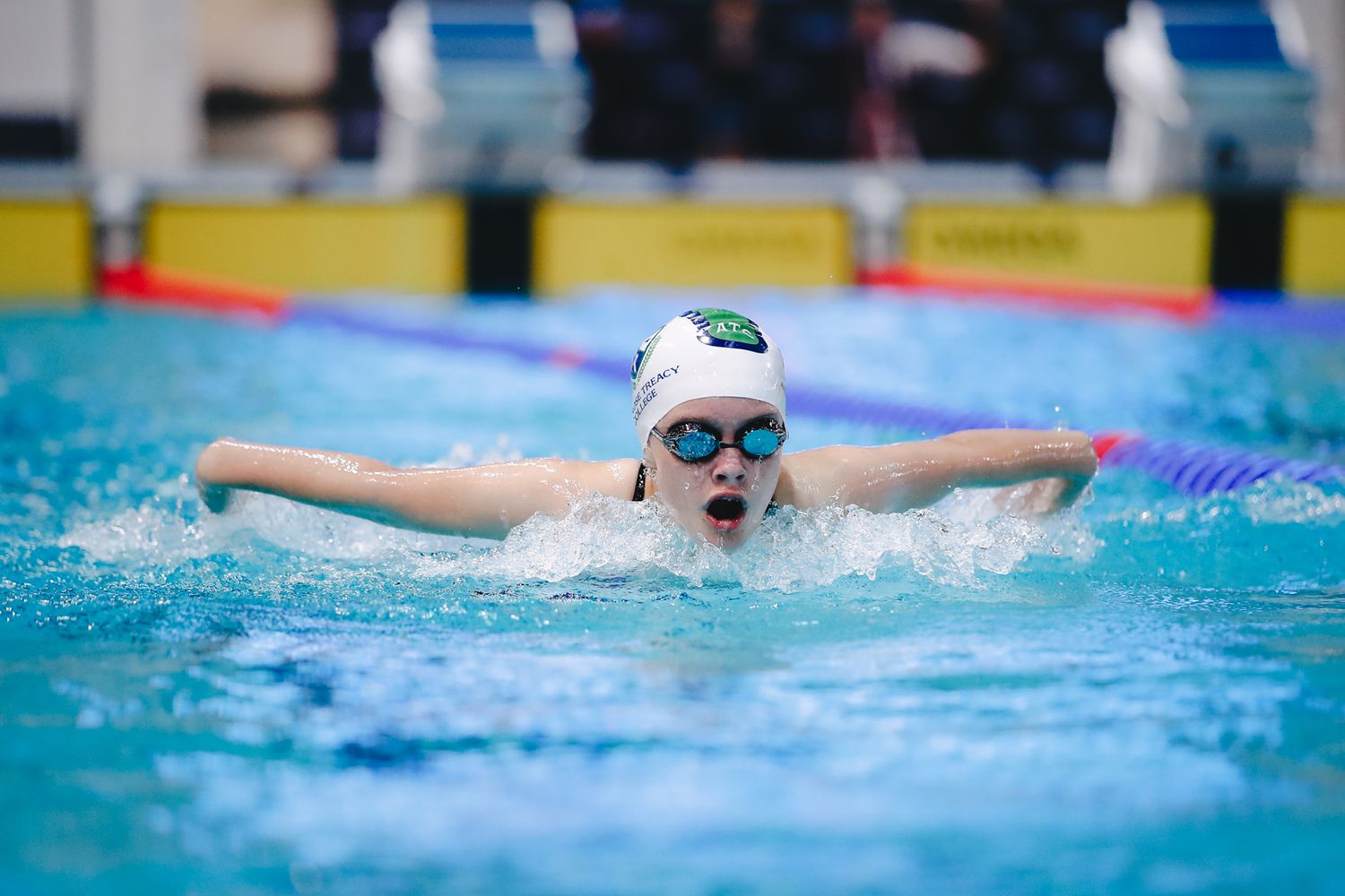 Swimmer performing butterfly stroke in competition pool with perfect form.