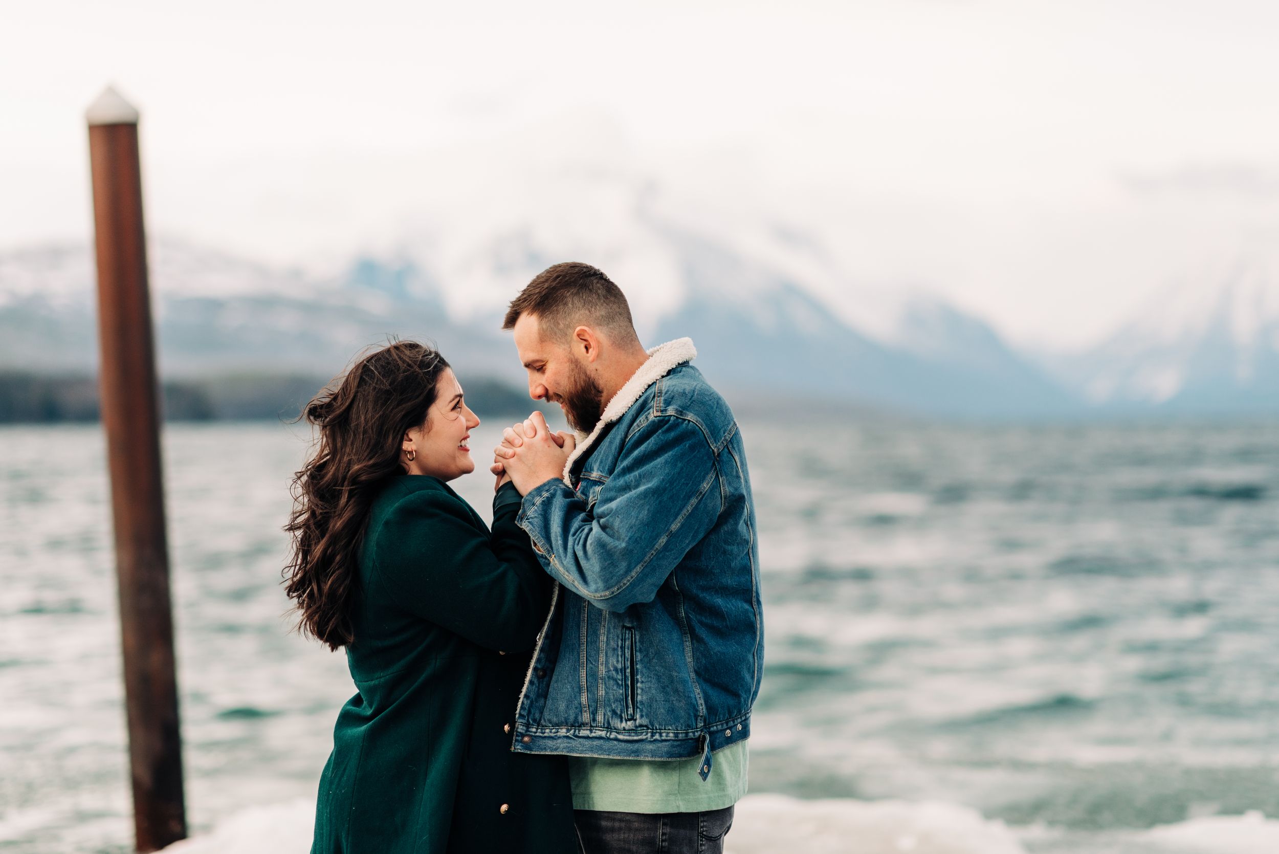 A tender moment shared between a couple on a dock with misty mountains in the background.