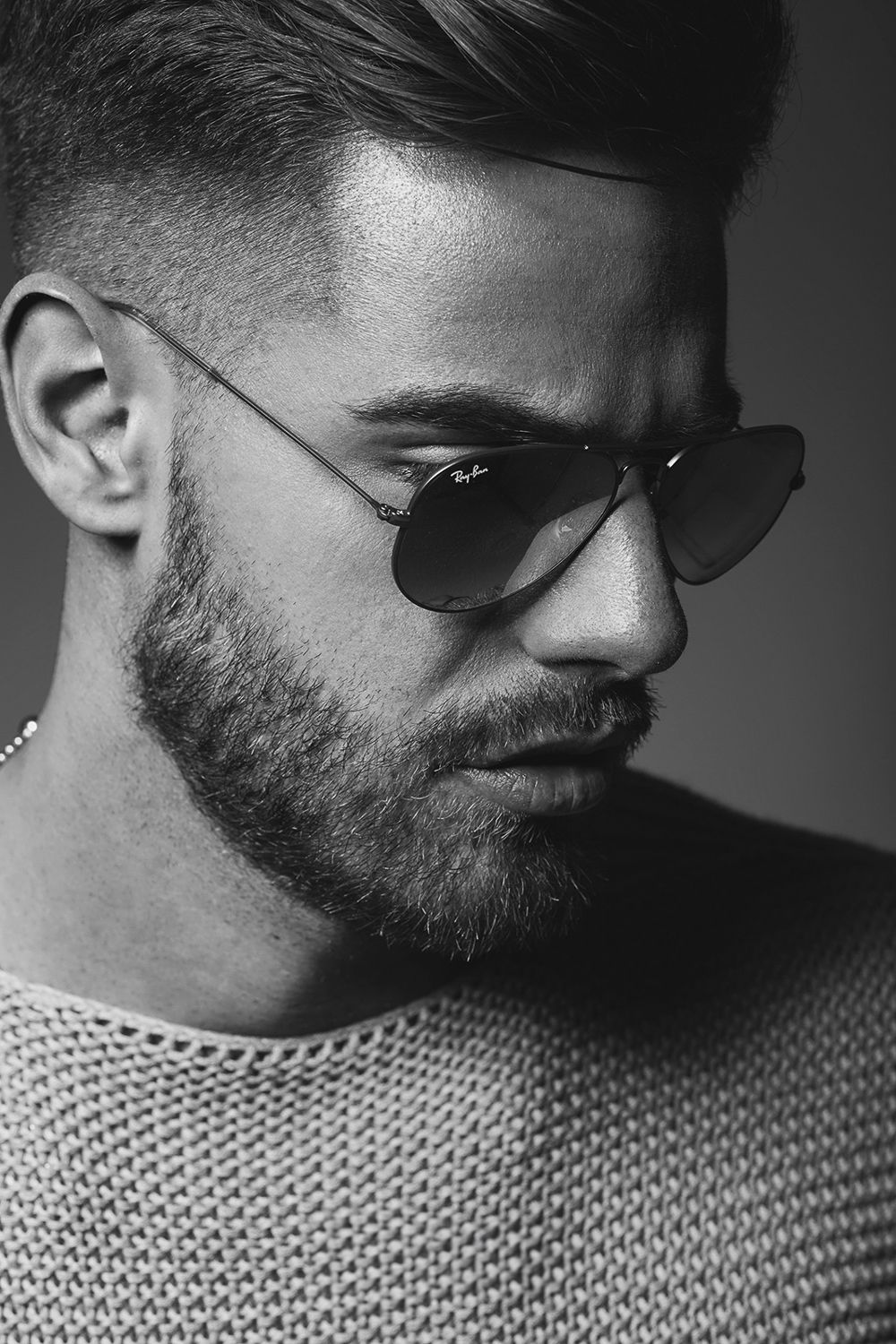 Bearded man wearing Ray-Ban aviator sunglasses in black and white close-up portrait.