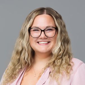 Portrait series showing joyful emotions of a person in glasses wearing pink against a gray background.