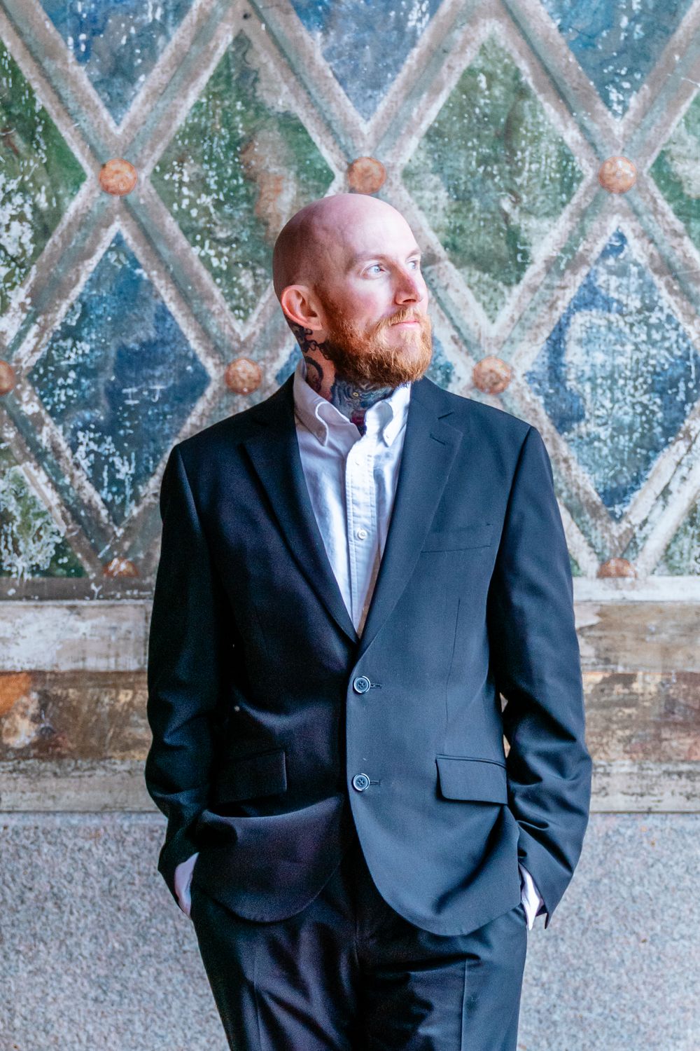 Stylish groom portrait with ornate patterned wall in Central Park