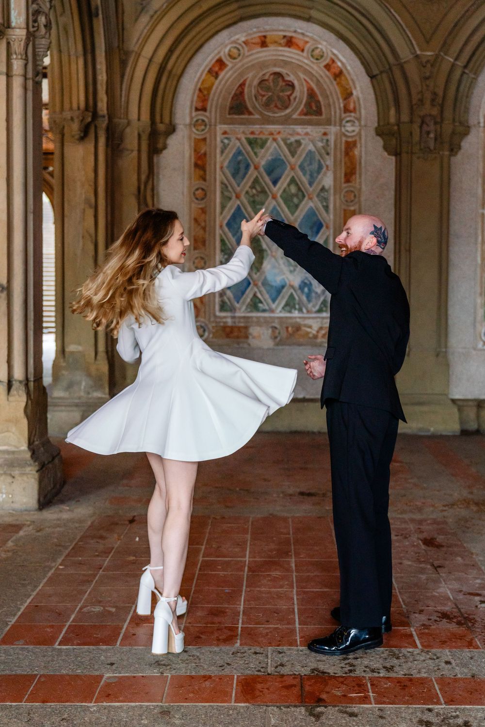 Couple dancing elegantly in white dress and black suit at ornate Bethesda Terrace, Central Park.