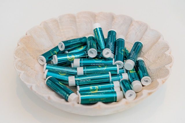 A white scalloped bowl filled with teal and white AA rechargeable batteries on a white background.