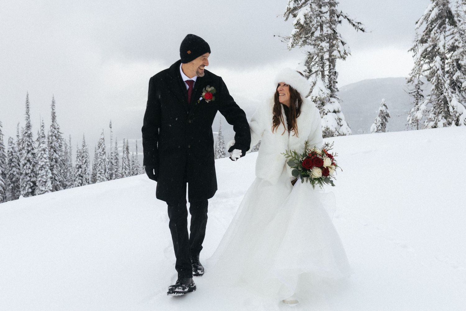 bride and groom walk along snowy path in Revelstoke, BC