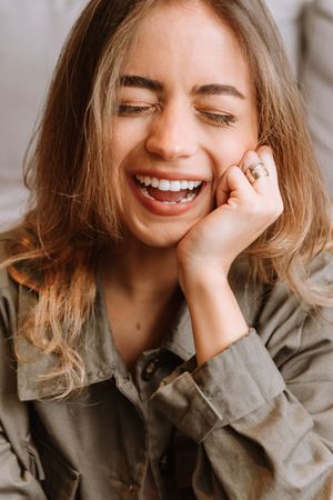 Candid portrait showing genuine laughter while wearing casual button-up shirt.